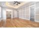 Large bedroom with custom paneling, hardwood floors, tray ceiling, and ample natural light at 14119 Shelburne Village Dr, Charlotte, NC 28278