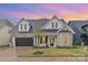Charming two-story home featuring a stone facade, black shutters, well-manicured lawn, and attached garage at 14119 Shelburne Village Dr, Charlotte, NC 28278