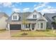 Charming two-story home featuring a stone facade, black shutters, well-manicured lawn, and attached garage at 14119 Shelburne Village Dr, Charlotte, NC 28278