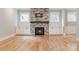 Living room showcasing a brick fireplace, white built-in cabinets, hardwood floors, and large windows at 14119 Shelburne Village Dr, Charlotte, NC 28278