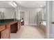 Spacious bathroom featuring a soaking tub, glass shower, double vanity and tile flooring at 1515 Millbridge Pkwy, Waxhaw, NC 28173