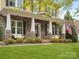 Inviting front porch with stone columns and white benches overlooking a well-manicured lawn at 1515 Millbridge Pkwy, Waxhaw, NC 28173
