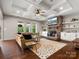 Bright living room boasts coffered ceiling, hardwood floors, stone fireplace, and tan leather couch at 1515 Millbridge Pkwy, Waxhaw, NC 28173