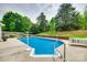 Relaxing in-ground pool surrounded by a concrete patio and lush landscaping provides a private backyard oasis at 15306 Gower Ct, Charlotte, NC 28278