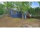 Backyard showcasing the home's blue exterior, deck, mature trees, and landscaped grounds at 1933 Thurmond Pl, Charlotte, NC 28205