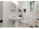 Bright bathroom featuring a pedestal sink, toilet, mirror, and a window with natural light at 1933 Thurmond Pl, Charlotte, NC 28205
