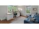 Sunlit office space with a large desk, ergonomic chair, blue sofa, and natural hardwood floors at 1933 Thurmond Pl, Charlotte, NC 28205