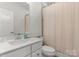Clean, bright bathroom featuring a vanity, toilet, and shower with a white and tan striped shower curtain at 2037 Birchside Dr, Charlotte, NC 28205