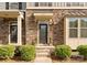 Inviting front door with stone facade, decorative plants, and manicured shrubs enhances curb appeal at 2037 Birchside Dr, Charlotte, NC 28205