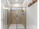 The shower is tiled with neutral tiles, has a glass door and multiple places to hold shower items at 2037 Birchside Dr, Charlotte, NC 28205