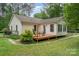 Backyard with a wooden deck, table and chairs, green grass, partial fencing and mature trees surrounding the property at 204 Millwheel Ln, Mount Gilead, NC 27306