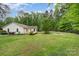 Large backyard featuring a green lawn, privacy fencing, mature trees, a wooden deck, and a fire pit area at 204 Millwheel Ln, Mount Gilead, NC 27306