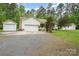 Exterior view of a home with multiple detached garages and ample parking space at 204 Millwheel Ln, Mount Gilead, NC 27306