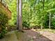 Lush backyard with mature trees, a wooden fence, and an exterior view of the house creates a peaceful outdoor space at 2731 Creekbed Ln, Charlotte, NC 28210