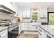 Well-lit kitchen with white cabinets, granite countertops, subway tile backsplash, stainless steel appliances, and a farmhouse sink at 2780 China Grove Rd, Kannapolis, NC 28083