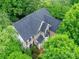An aerial view of a large brick home with dark shutters, surrounded by trees, and a dark gray roof at 3203 Blackburn Dr, Waxhaw, NC 28173