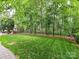 A spacious backyard featuring lush green grass, mature trees, an outdoor fireplace and black metal fencing at 3203 Blackburn Dr, Waxhaw, NC 28173