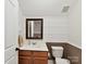This bathroom features a vanity with wood cabinets, mirror, sink, toilet and white plank accent wall at 3203 Blackburn Dr, Waxhaw, NC 28173
