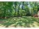 Open backyard space with grassy areas and mature trees and a view of the back deck at 3317 Treyburn Dr, Midland, NC 28107