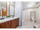Bathroom featuring dual sinks, wood cabinets, and a shower, all complemented by unique patterned wallpaper at 3317 Treyburn Dr, Midland, NC 28107