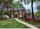 Charming brick home with well-manicured lawn, colorful azaleas, and paved walkway at 3804 Bellingham Ln, Charlotte, NC 28215