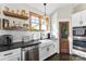 Well-lit kitchen featuring white cabinets, stainless steel appliances, floating shelves, and a farmhouse sink at 4453 Buffalo Shoals Rd, Maiden, NC 28650