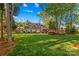 Expansive backyard with a well-manicured lawn, mature trees providing shade, and a view of the home's rear facade at 7896 Harbor Master Ct, Denver, NC 28037