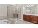 Neutral tiled bathroom with glass shower, soaking tub, and wood vanity with dual lights at 7896 Harbor Master Ct, Denver, NC 28037