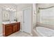 Bright bathroom featuring a vanity with wood cabinets, soaking tub and stylish fixtures at 7896 Harbor Master Ct, Denver, NC 28037