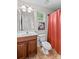 Cozy bathroom featuring a vanity with wood cabinets, toilet and shower with red curtain at 7896 Harbor Master Ct, Denver, NC 28037