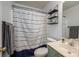Well-lit bathroom featuring a shower with blue and white curtain and floating shelves at 7905 Sedgebrook E Dr, Stanley, NC 28164