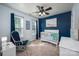 Bedroom boasts blue accent wall, white crib, a glider chair, a ceiling fan, and natural light at 7905 Sedgebrook E Dr, Stanley, NC 28164