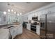Contemporary kitchen with stainless steel appliances, white cabinets, and hardwood floors open to dining area at 7905 Sedgebrook E Dr, Stanley, NC 28164