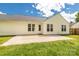 A concrete patio with a door and windows overlooking a lush green lawn under a sunny sky at 9916 Meadowmead Ct # 17, Charlotte, NC 28273
