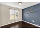 This bedroom features a board and batten accent wall, floating shelves, window, and dark wood-look flooring at 9916 Meadowmead Ct # 17, Charlotte, NC 28273