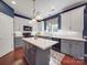 Modern kitchen with white cabinets, gray island, quartz countertops, stainless steel appliances, and hardwood floors at 1103 Cooper Ln, Indian Trail, NC 28079