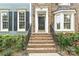 A front entrance with brick steps and black railings, leading to a door with sidelights, complemented by flowering bushes at 11232 Tradition View Dr, Charlotte, NC 28269
