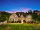 Beautiful brick home featuring manicured landscaping and mature trees at dusk at 1128 Rosecliff Dr, Marvin, NC 28173