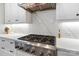 Close-up of a professional-grade stainless steel stove with marble backsplash and white cabinets at 1149 Grand Oak Dr, Waxhaw, NC 28173
