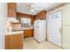 Kitchen with wood cabinets, white appliances, and an adjacent door to the exterior at 1214 Short St, Salisbury, NC 28144