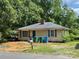 Quaint single-story home featuring green trim, a brick chimney, and a mature tree-lined yard at 1224 Bailey St, Albemarle, NC 28001