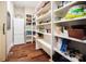 Walk-in pantry with open shelving, refrigerator, and hardwood flooring for ample storage and organization at 13106 Bien Ct, Huntersville, NC 28078