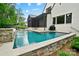 A refreshing pool with stone accents sits beside a modern home and outdoor cooking space, ready for summer fun at 13106 Bien Ct, Huntersville, NC 28078