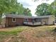 Backyard view of a brick home with a wooden deck and lush greenery at 1400 Lackey St, Shelby, NC 28152