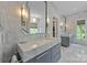 Bright bathroom featuring marble walls, dual sinks, a window with a view, and a glimpse into the closet at 1550 High St, Charlotte, NC 28211