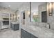 Bright bathroom featuring marble walls, dual sinks, a window with a view, and a glimpse into the bedroom at 1550 High St, Charlotte, NC 28211