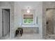 Bathroom featuring marble walls, a bathtub under a window with a view, and a glass enclosed shower at 1550 High St, Charlotte, NC 28211