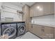 Well-equipped laundry room with gray washer and dryer, gray cabinets, and gray tiled floors at 1550 High St, Charlotte, NC 28211