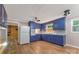 A full view of the vintage kitchen featuring painted blue cabinets, a white refrigerator, and hardwood floors at 1713 Wildwood Dr, Albemarle, NC 28001