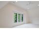 Bright bedroom featuring three large windows, a ceiling fan, and neutral colored walls and carpet at 1807 Arnold Dr, Charlotte, NC 28205